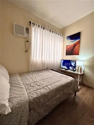 a bedroom with a bed and a window with a fan at C homestay fullerton suites in Silang