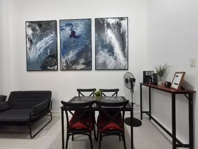 a room with a table and four paintings on the wall at Forbeswood Garden Suite Parklane BGC in Manila