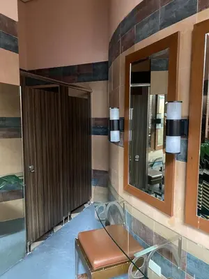 a bathroom with a brown door and a mirror at Forbeswood Garden Suite Parklane BGC in Manila