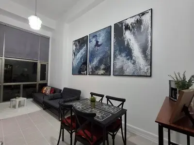 a living room with a table and four paintings on the wall at Forbeswood Garden Suite Parklane BGC in Manila