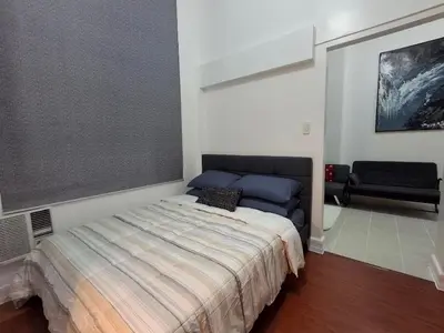 a bedroom with a bed and a couch in it at Forbeswood Garden Suite Parklane BGC in Manila
