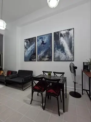 a living room with a table and four paintings on the wall at Forbeswood Garden Suite Parklane BGC in Manila