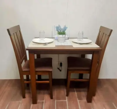 a wooden table with two chairs with plates and glasses on it at Condo in Makati, Casa Beatrice in Manila