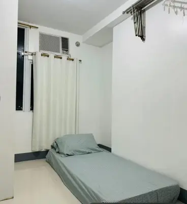 a bed in a white room with a window at Casa Lily in Manila