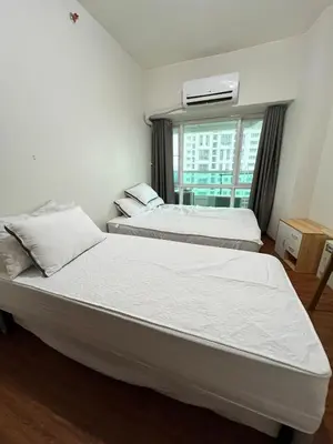two beds in a room with a window at Tower 1 Rm 305 FREE Parking, FREE Pool, Balcony, 1Bedroom 4 beds in Manila