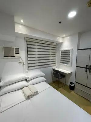 a white bedroom with a bed and a desk at M&M Suites Ridgewood Towers T3 BGC McKinley in Manila