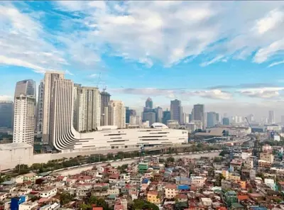 a city with a large white building in the foreground at M&M Suites Ridgewood Towers T3 BGC McKinley in Manila