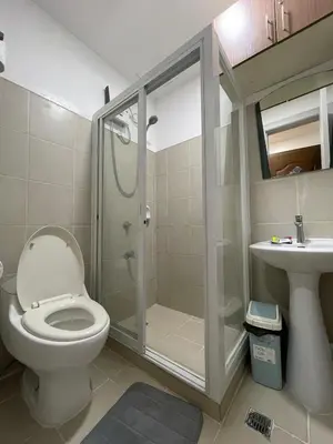 a bathroom with a toilet and a shower and a sink at M&M Suites Ridgewood Towers T3 BGC McKinley in Manila