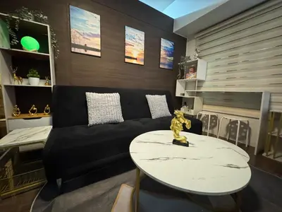 a living room with a black couch and a table at Luxurious 2 Bedroom Oasis in Air Residences with Bar KTV and Games in Manila