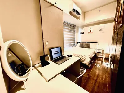 a room with a bed and a desk with a laptop at Luxurious 2 Bedroom Oasis in Air Residences with Bar KTV and Games in Manila