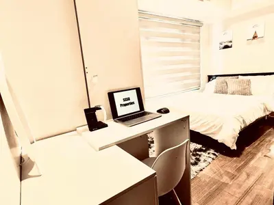 a bedroom with a desk with a laptop on it at Luxurious 2 Bedroom Oasis in Air Residences with Bar KTV and Games in Manila
