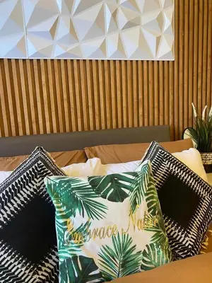 a bed with a pillow with palm leaves on it at Twin Oaks near MRT Shaw, Megamall, Shangri-la plaza in Manila