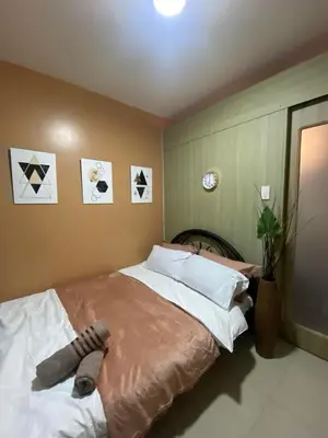 a bedroom with a large bed with white pillows at COZY PASAY CONDOMINIUM HOTEL UNIT with NETFLIX in Manila