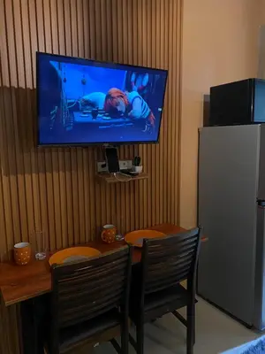a kitchen with a table and a television on a wall at COZY PASAY CONDOMINIUM HOTEL UNIT with NETFLIX in Manila