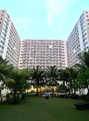a person walking in front of a large building at COZY PASAY CONDOMINIUM HOTEL UNIT with NETFLIX in Manila