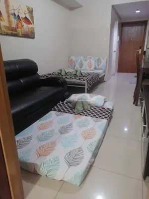 a living room with two beds and a couch at 2 bedroom just accross MOA and SMX by jam ez in Manila