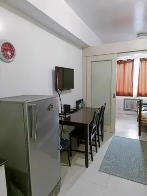a kitchen and dining room with a table and a refrigerator at 2 bedroom just accross MOA and SMX by jam ez in Manila