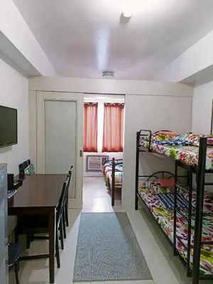 a room with two bunk beds and a table and a dining room at 2 bedroom just accross MOA and SMX by jam ez in Manila