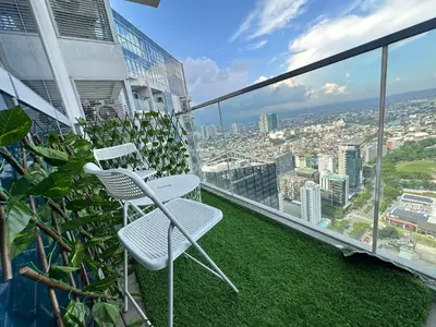 a balcony with two chairs and a view of a city at City Lights Apartment in BGC in Manila