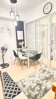 a dining room with a table and chairs and a clock at Art & Zen - Azure Staycation in Manila