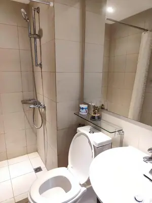 a bathroom with a shower and a toilet and a sink at Cozy fully furnished 2 BR unit in Manila