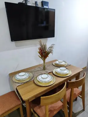 a wooden table with plates and a television on a wall at Cozy fully furnished 2 BR unit in Manila