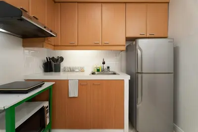 a kitchen with wooden cabinets and a refrigerator at Studio Penthouse in Greenbelt - Park View & Pool in Manila