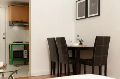 a dining room table with black chairs and a kitchen at Studio Penthouse in Greenbelt - Park View & Pool in Manila