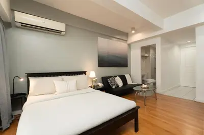 a bedroom with a large white bed and a couch at Studio Penthouse in Greenbelt - Park View & Pool in Manila