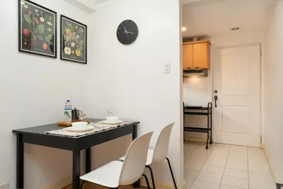 a kitchen with a table and chairs and a clock on the wall at Tranquil Greenbelt Makati Condo - Free Pool Access in Manila