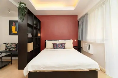 a bedroom with a large bed and a red wall at Tranquil Greenbelt Makati Condo - Free Pool Access in Manila