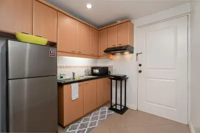 a kitchen with wooden cabinets and a stainless steel refrigerator at Greenbelt Makati Condo with Balcony & Park Views in Manila