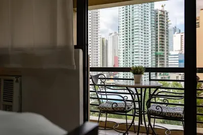 a table and chairs on a balcony with a view of a city at Greenbelt Makati Condo with Balcony & Park Views in Manila