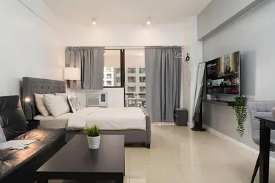 a living room with a bed and a couch at Charming Greenbelt Condo with Balcony & Pool Access in Manila
