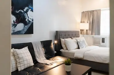 a living room with a couch and a bed at Charming Greenbelt Condo with Balcony & Pool Access in Manila