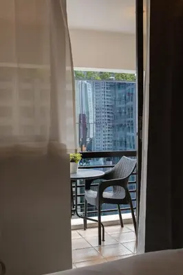 a chair sitting on a balcony with a table at Charming Greenbelt Condo with Balcony & Pool Access in Manila