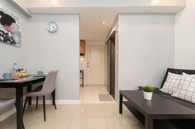 a living room with a table and a dining room at Charming Greenbelt Condo with Balcony & Pool Access in Manila