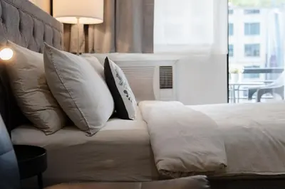 a bed with white pillows on it in a room at Charming Greenbelt Condo with Balcony & Pool Access in Manila