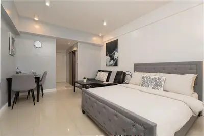 a bedroom with a large bed and a dining room at Charming Greenbelt Condo with Balcony & Pool Access in Manila