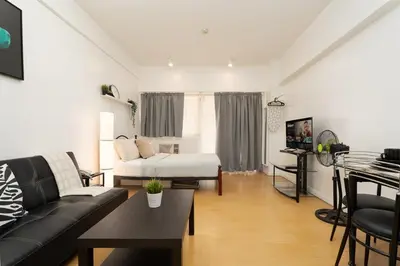 a living room with a couch and a bed at Comfy Greenbelt Suite - Fiber Wifi & Free Pool in Manila