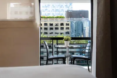 a table and chairs on a balcony with a view of a city at Comfy Greenbelt Suite - Fiber Wifi & Free Pool in Manila