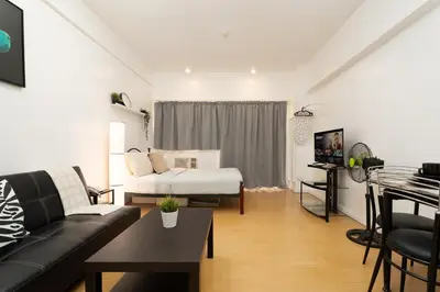 a living room with a couch and a bed at Comfy Greenbelt Suite - Fiber Wifi & Free Pool in Manila
