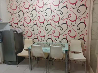 a dining room table with chairs and a red swirl wallpaper at Sea Residence Tower EF by Theresa P in Manila