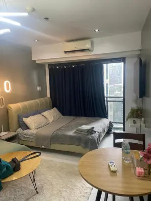 a bedroom with a large bed and a table at Studio for 4 with Netflix, 55in TV, 200Mbs net, in heart of Makati in Manila