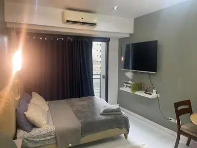 a bedroom with a bed and a tv and a window at Studio for 4 with Netflix, 55in TV, 200Mbs net, in heart of Makati in Manila
