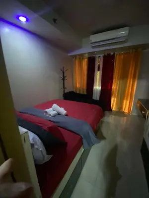 a bedroom with a red bed with a stuffed animal on it at 257-1BR 2 Queen size bed 1sofa bed 1 extra matress in Manila