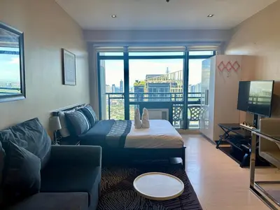 a bedroom with a bed and a couch and a tv at Studio Unit with Balcony in The Gramercy Residences in Manila