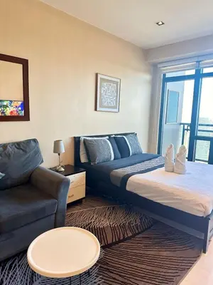 a bedroom with a bed and a couch at Studio Unit with Balcony in The Gramercy Residences in Manila
