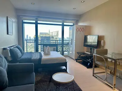 a room with a bed and a couch and a television at Studio Unit with Balcony in The Gramercy Residences in Manila