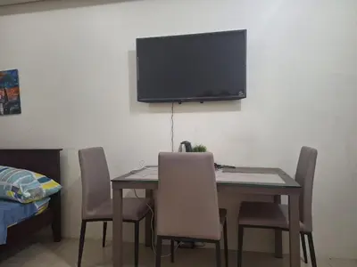 a dining room table with chairs and a television on the wall at Chelsea Suites at the Beacon Makati in Manila
